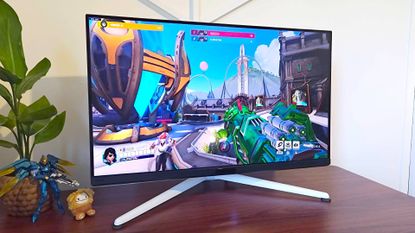 BenQ Mobiuz EX321UX monitor on desk with Overwatch 2 gameplay on screen.
