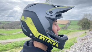 Side view of rider wearing a Giro Insurgent Spherical full-face helmet with countryside backdrop