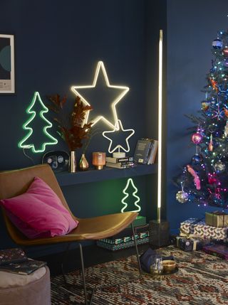 An assortment of Christmas-themed neon lights in living room with Aztec patterned rug and Christmas tree