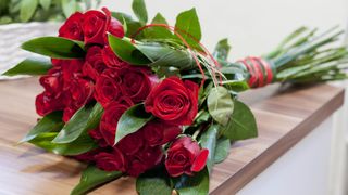 A bouquet of red roses tied up with string on a kitchen counter
