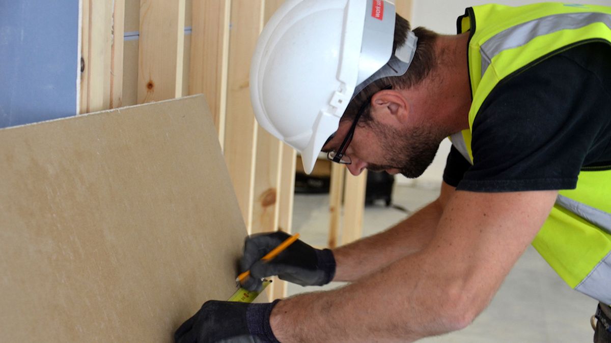 Man in hard hat measuring plasterboard alternative Breathaboard