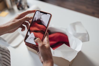 Person photographing packaged clothing using a smartphone