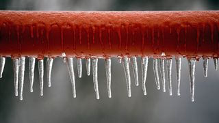 Frozen water icicles on brown pipe