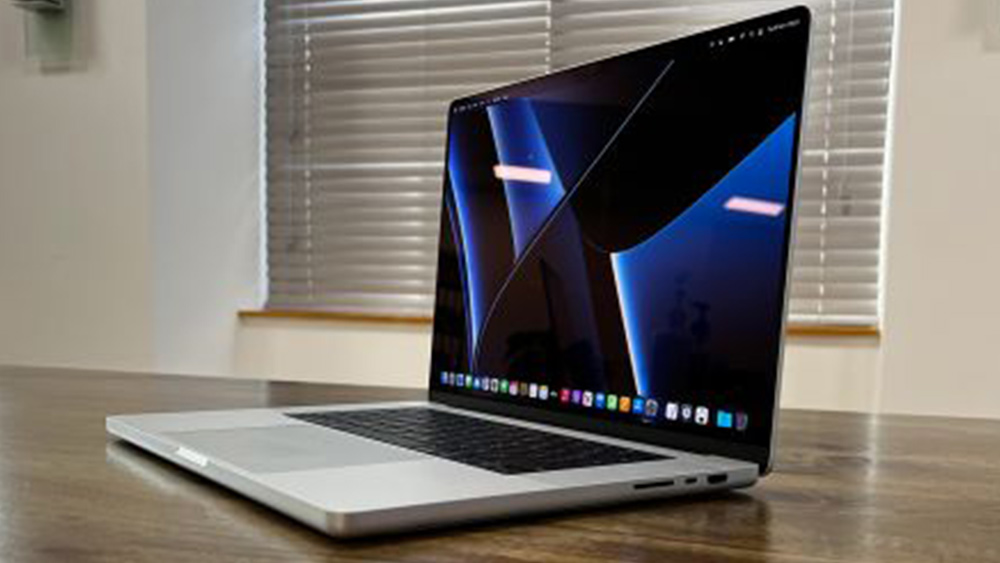 MacBook Pro 16 on a wooden desk with blinds in the background