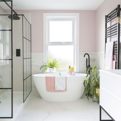 Houseplants in bathroom including calathea plant next to freestanding bath