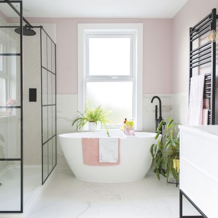 Houseplants in a white and pink bathroom including calathea plant next to large contemporary freestanding bath