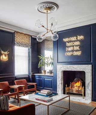 A blue living room with a sputnik chandelier, neon sign and fireplace