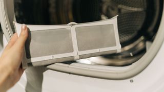 picture of woman holding lint drawer full of lint from dryer