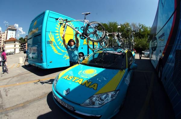 An Astana mechanic hoists a bike off the team car