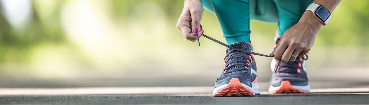 A close-up picture of a woman tying her running shoes