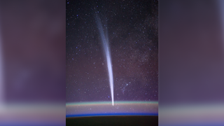 a bright fuzzy streak can be seen oriented from top to bottom of a picture of the starry night sky