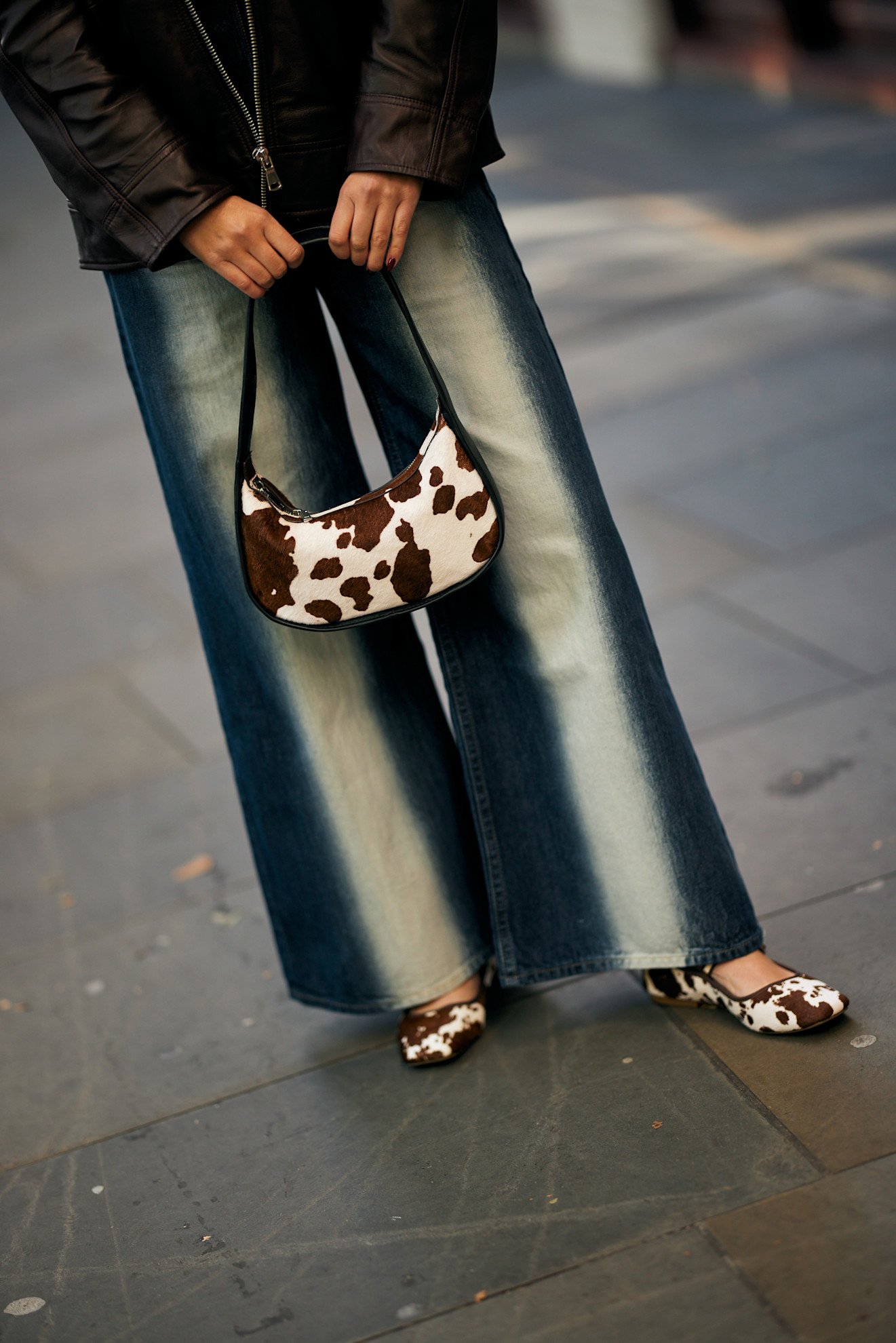 a woman wearing a cow print bag, jeans, cow print flats