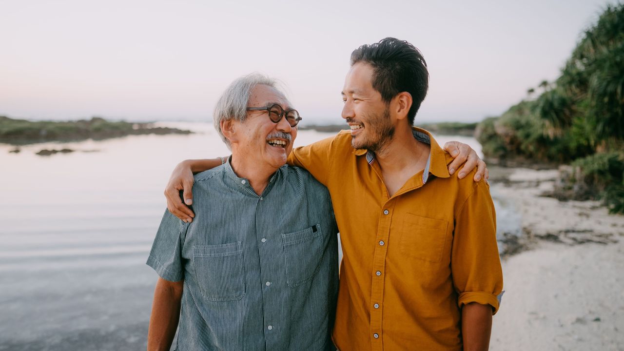 An older man walking with his adult son outdoors.