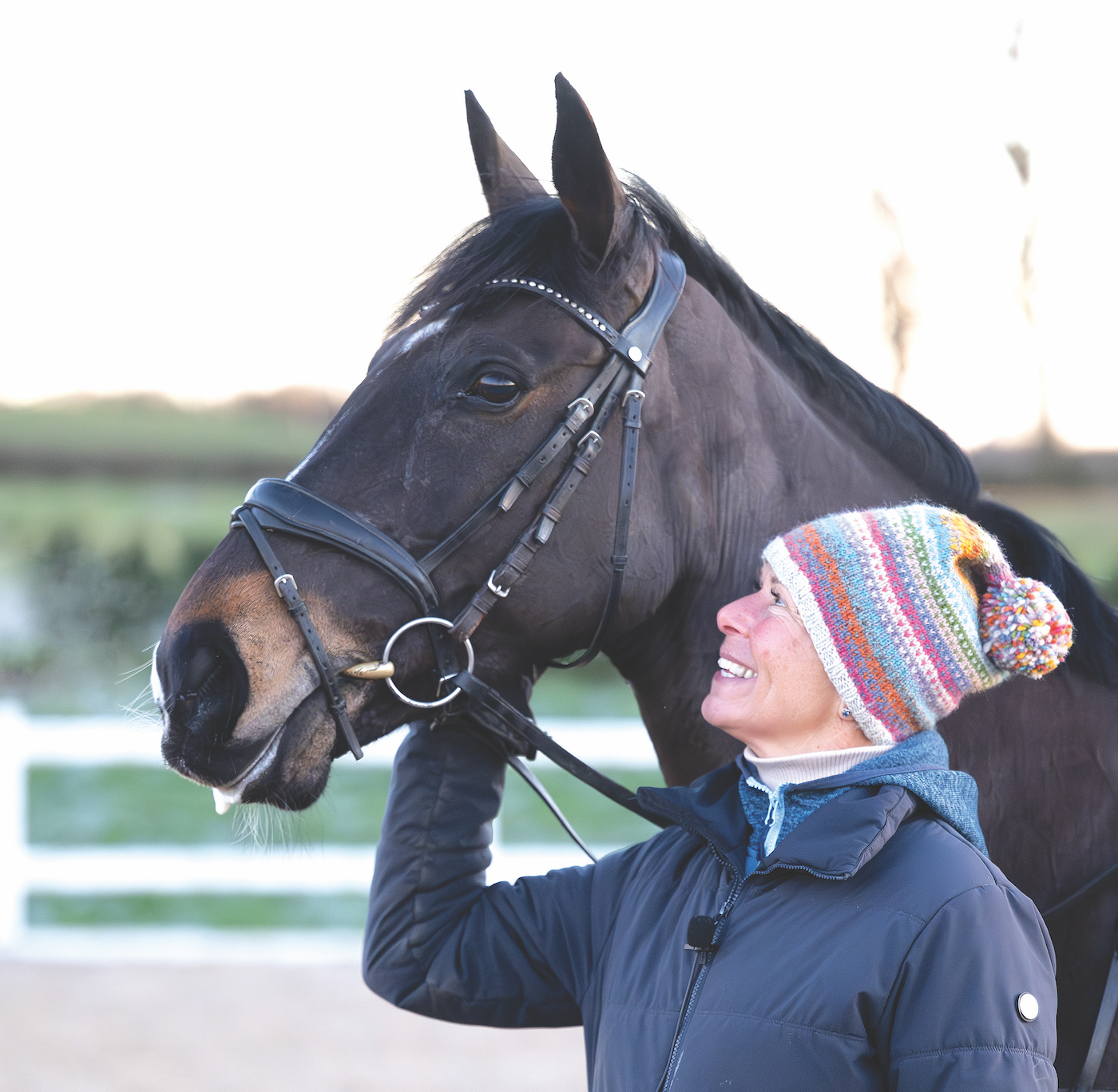 The late Caroline Moore smiles as she looks up at a bay horse's head