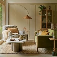 Neutral living room decorated for autumn with green velvet sofa, armchair in a William Morris fabric and marble coffee table