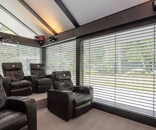 A cinema room with shutter blinds and leather sofas