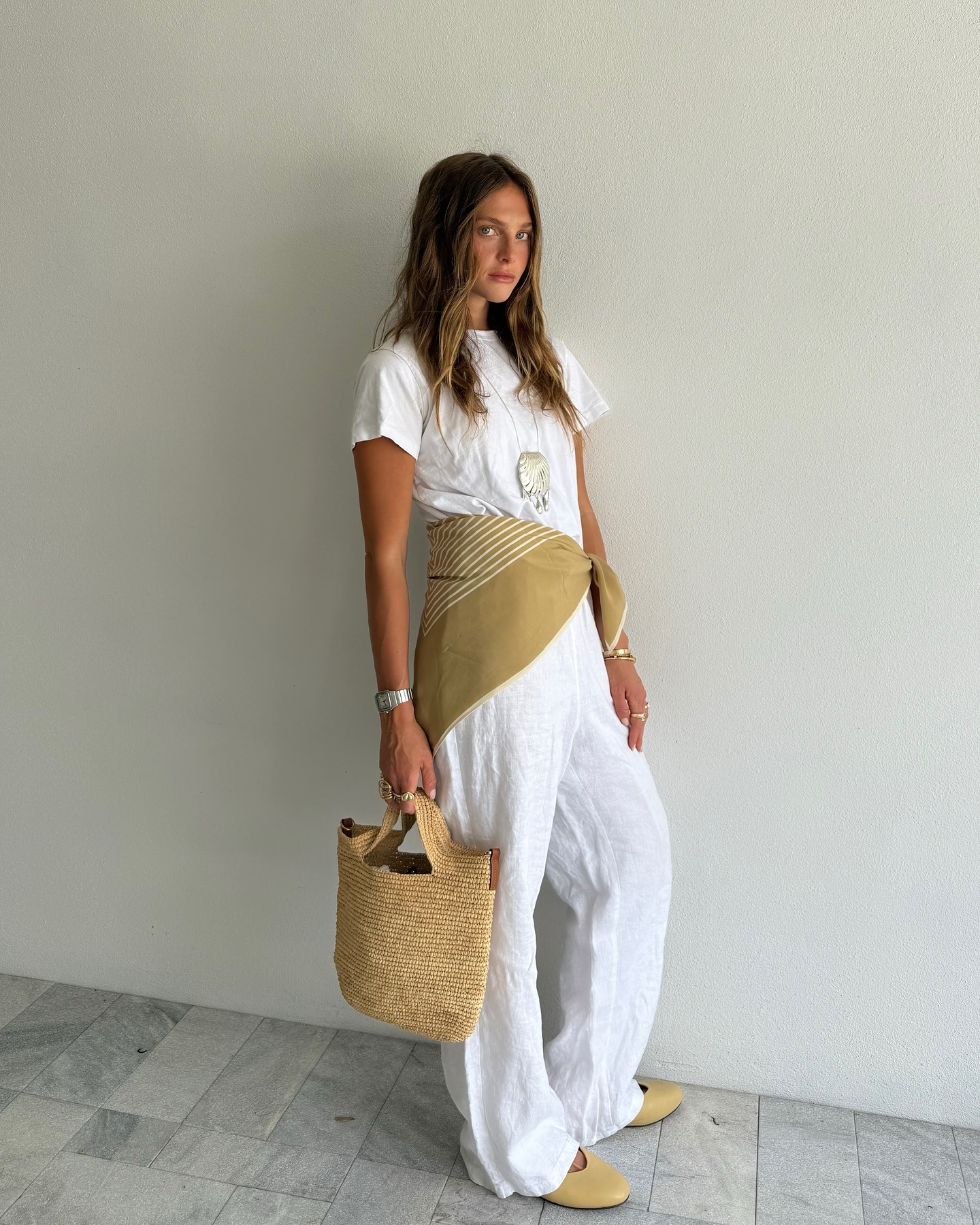 Woman in white linen pants, white t-shirt, and silk scarf.