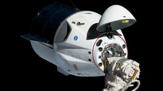 crew dragon with hatch open berthed with canadarm2 at international space station
