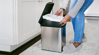 Lower half of someone removing the bag out of a bin container