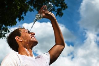 A man pours water over his head on a hot day.