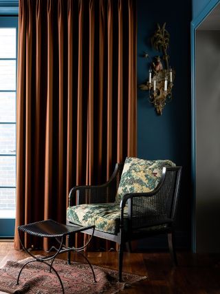 A living room with a thick curtain and a chair