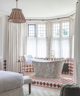 corner of a bedroom with brown and white chequered tiling surrounding freestanding bath tub