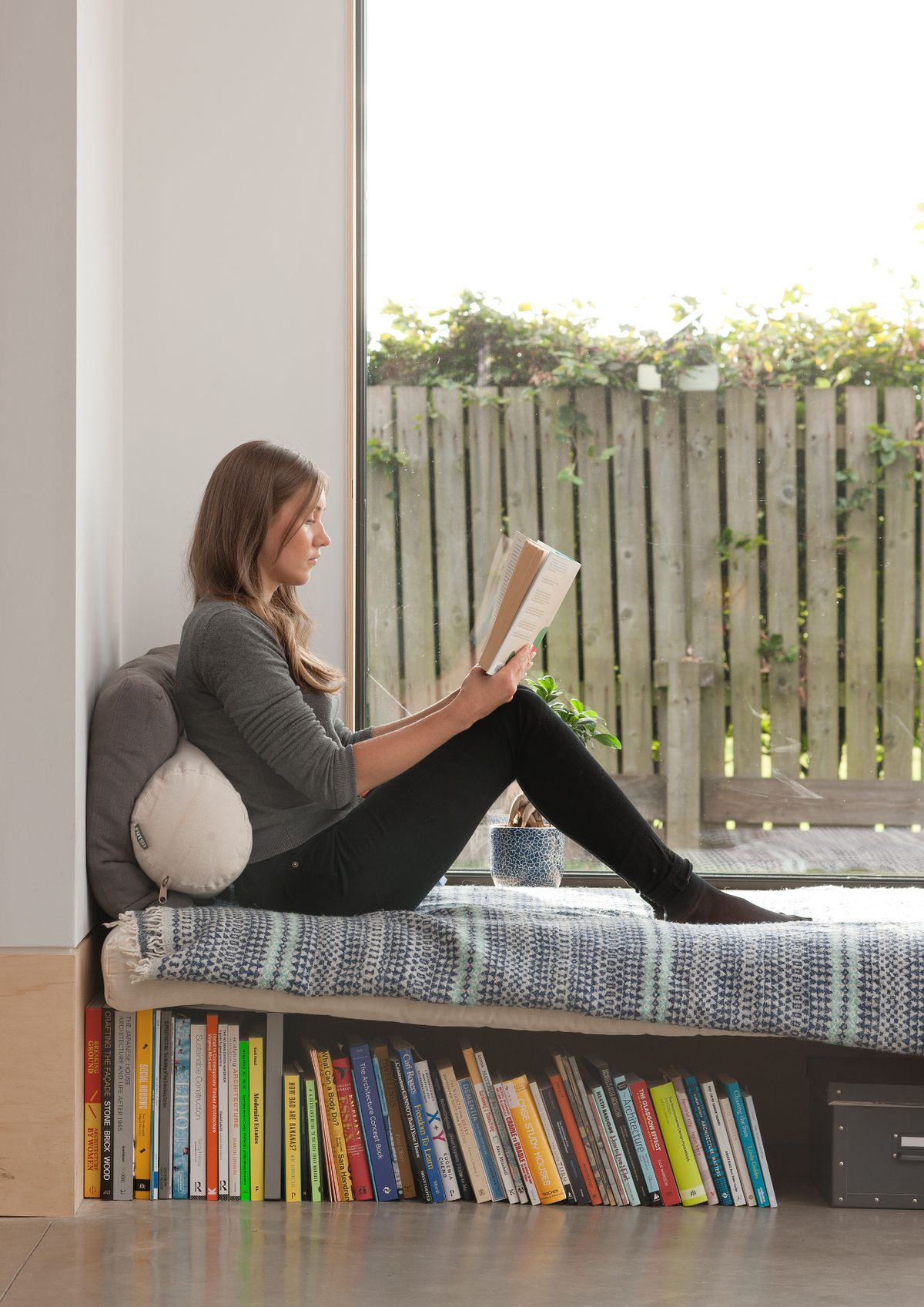 A woman sitting in a window seat with a book