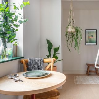 white wall with hanging plant and wooden table with spoons and plates
