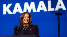 Kamala Harris smiling in from of a blue background with Kamala in white text