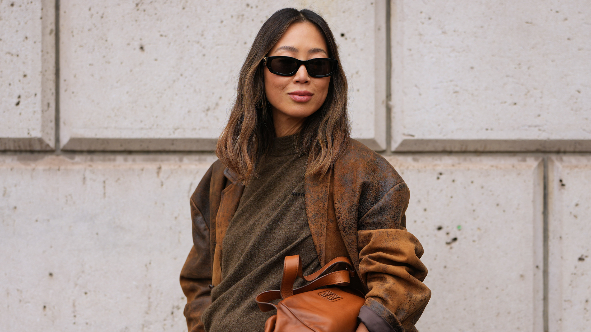 A woman wearing a brown cashmere sweater and sunglasses. 