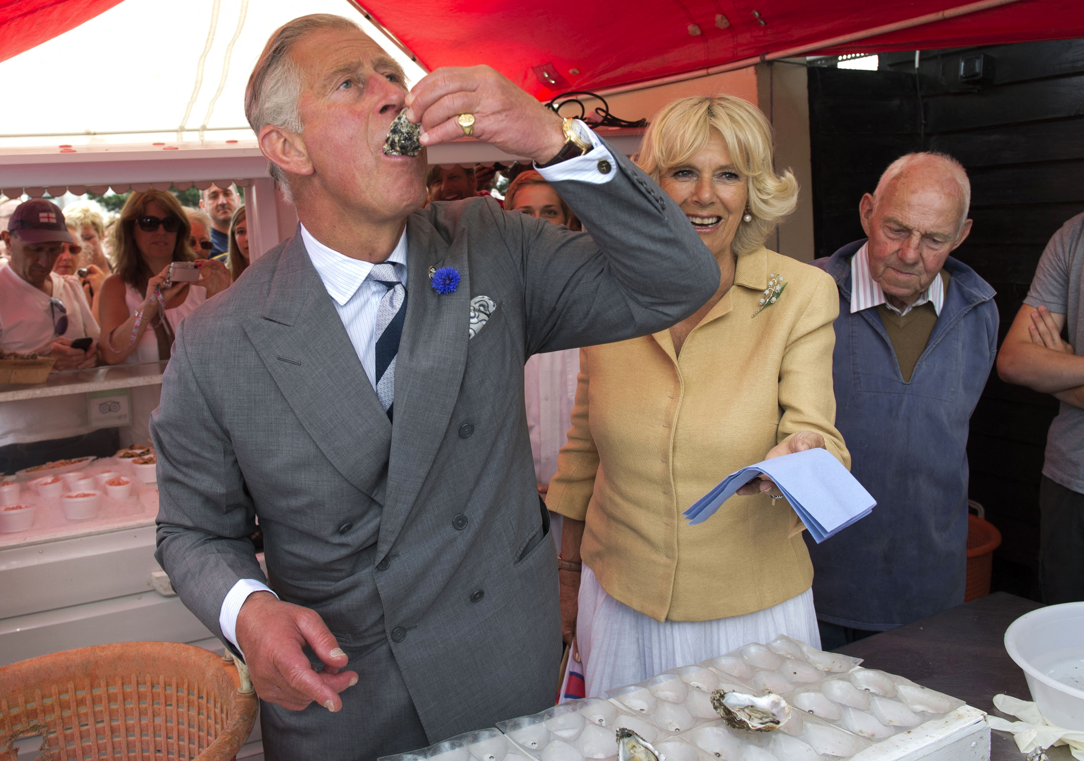 King Charles eating oysters standing next to Queen Camilla