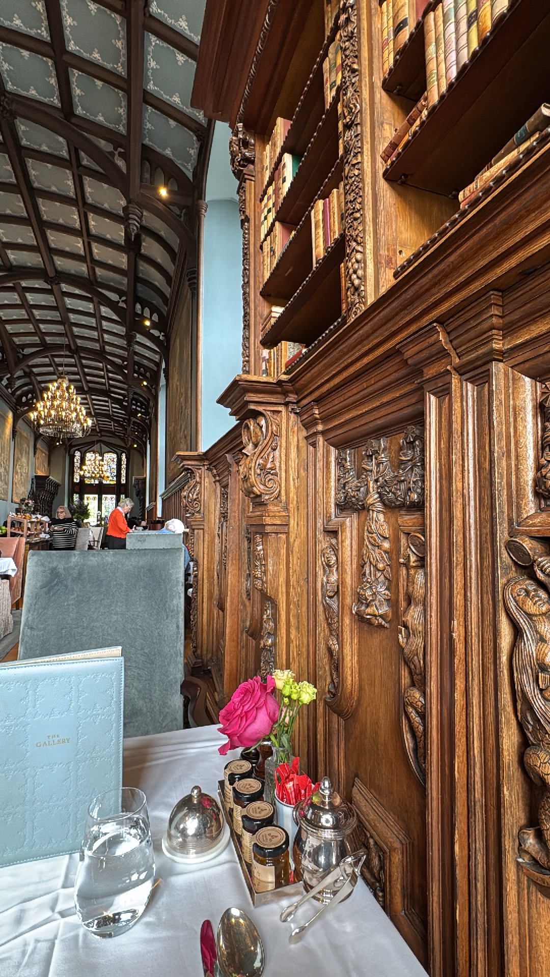 Carved wood shelves next to a breakfast table in a long room with an arched ceiling