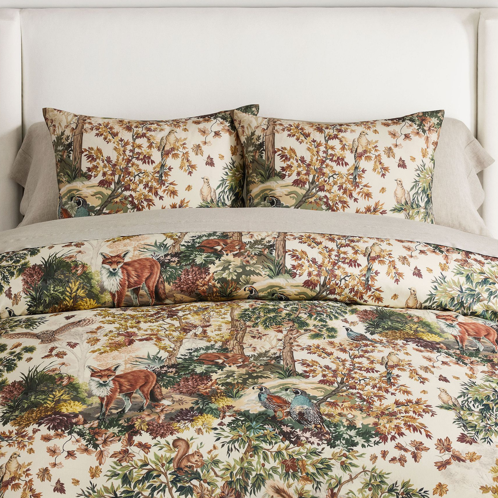 a bed with a forest design on the duvet cover and two pillows