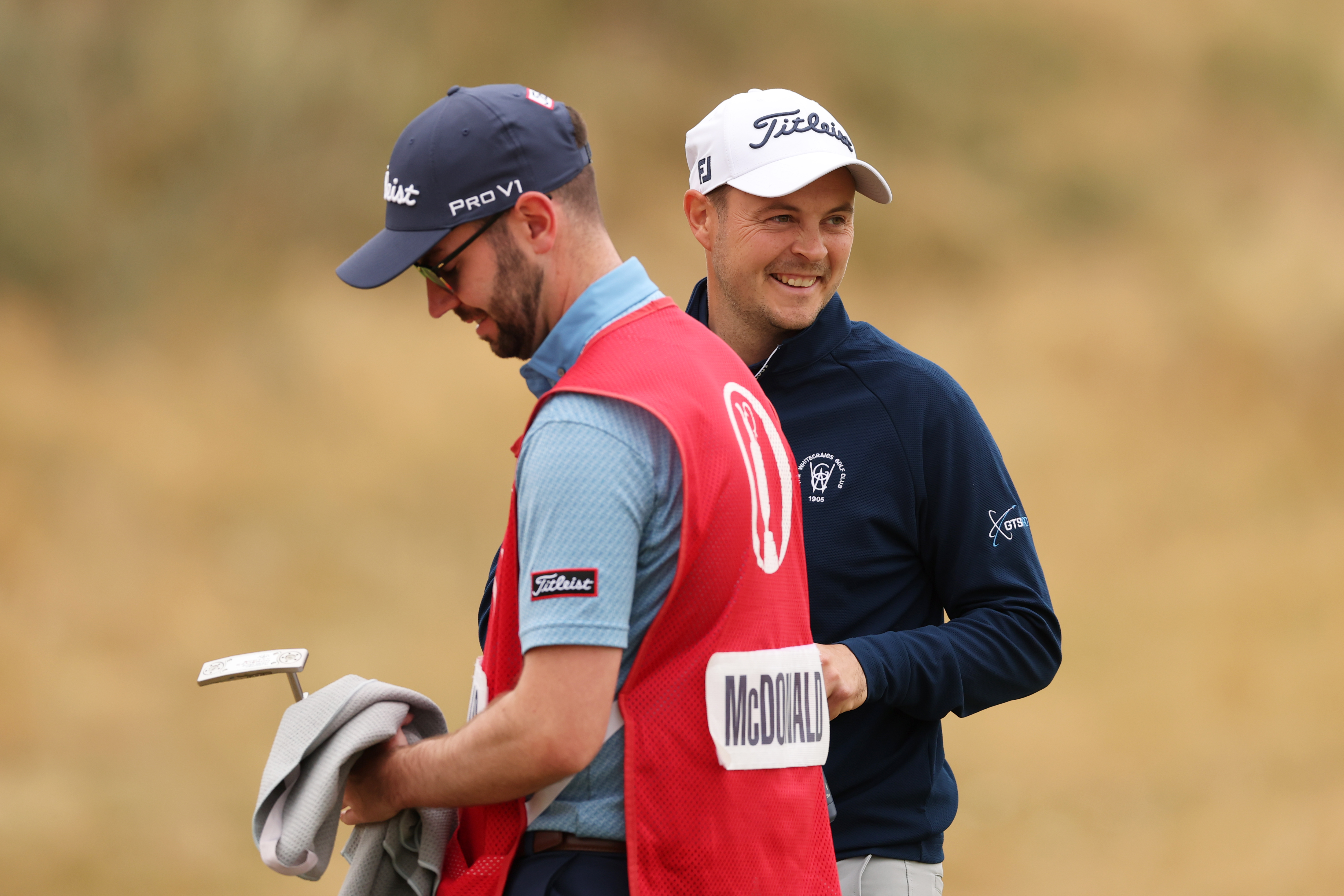 Jack McDonald smiles behind his caddie during The Open Championship in 2026