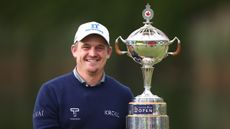 Bud Cauley smiling, stood next to the RBC Canadian Open trophy