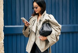 Woman in trench coat looking at phone