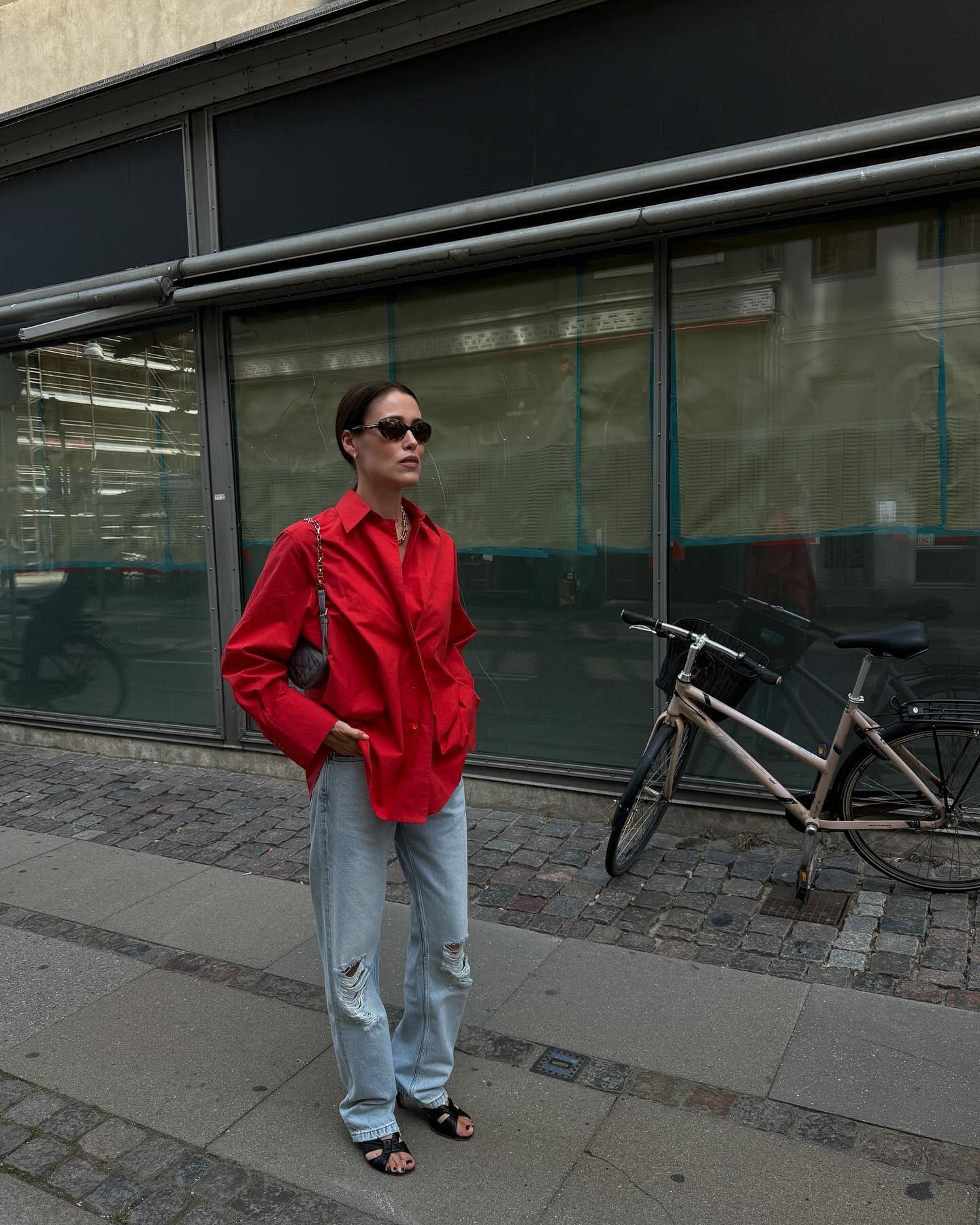 Annabel wears a red top, and ripped jeans with black heels.
