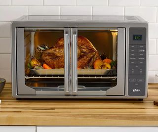 Oster French door air fryer cooking a rotisserie chicken.