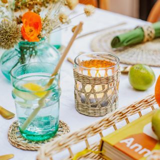 Glass with straw next to candle on white table