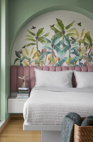 A bedroom with an arch painted green, and a headboard in pink