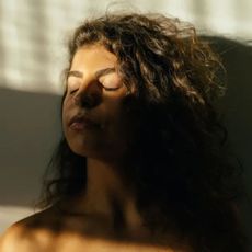 Woman enjoying sunlight through the window - skin inflammation