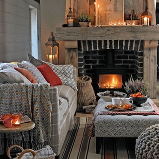 A country cottage living room with cosy layers, log burner next to white sofa and table