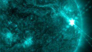 close-up view of the sun, with a powerful solar flare erupting from a spot on its right side.