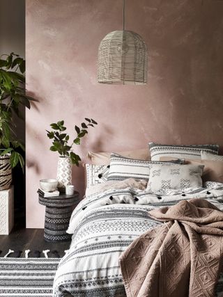 Bedroom in boho style with pink walls and monochrome sheets