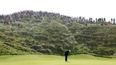Shane Lowry hits a putt with fans watching on
