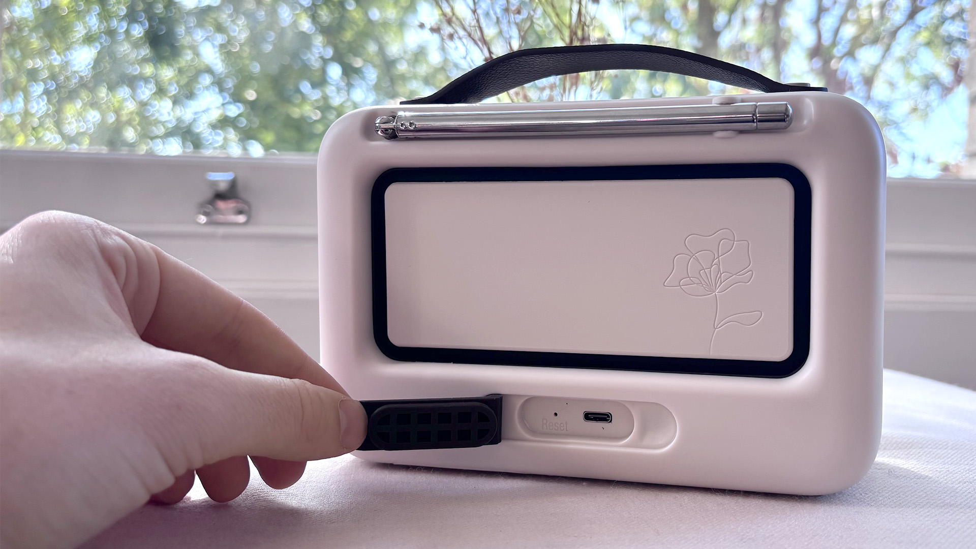 Pure Bloom DAB radio rear of unit with hand peeling back silcone cover to expose connection