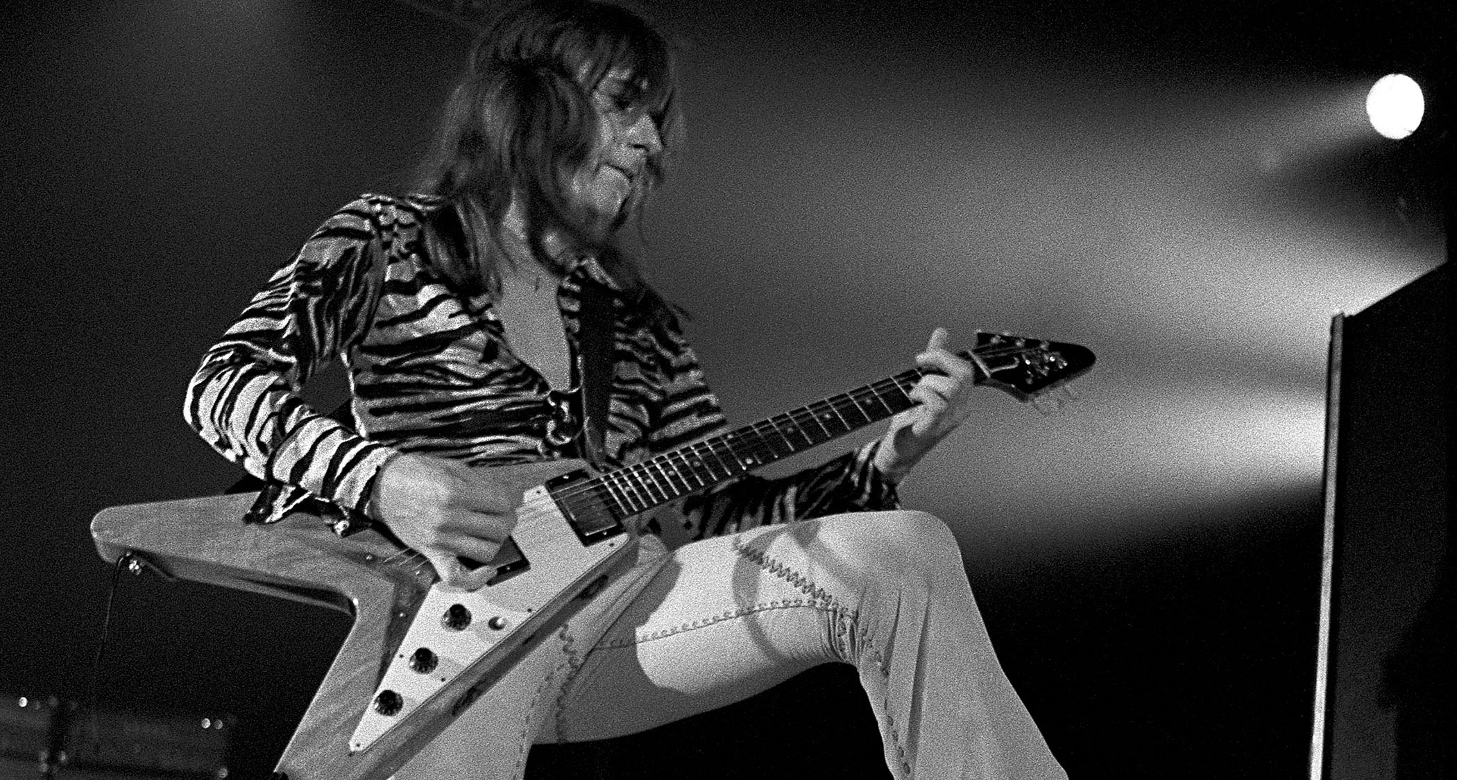 Mick Ralphs performs with Bad Company in 1975. He wears a tiger-print shirt and plays a Gibson Flying V.