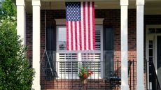 A traditional brick home with an American flag in the window