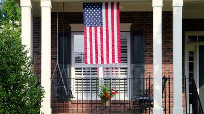 A traditional brick home with an American flag in the window