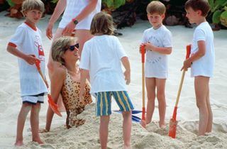 Diana, Princess Of Wales, Being Buried In The Sand By Her Sons, Prince William And Prince Harry During A Holiday On Necker Island. Princess Diana Is Wearing A Leopard Sking Swimming Costume